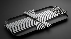 stainless steel metal skewers set on black tray professional food grilling equipment cooking tool accessories and barbecue preparation concept